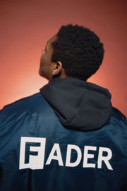 back of man wearing FADER x Alpha MA navy flight jacket with FADER logo