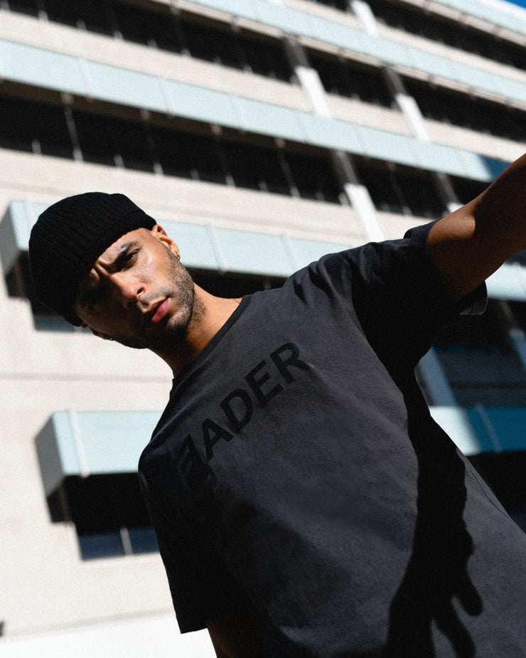 man wearing vintage black tee with black FADER logo on chest